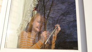 年轻的女人看着窗外画风景而外面的景色与树木反射在玻璃中14秒视频
