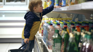 超市里的小男孩把一瓶矿泉水放进购物篮里24秒视频