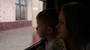 年轻的母亲和她的小儿子在火车上看着窗外的雨14秒视频