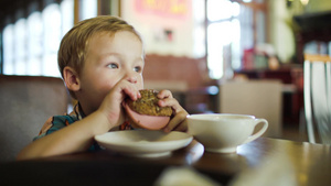 小男孩坐在咖啡馆里吃三明治25秒视频
