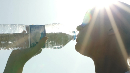 戴太阳镜的女人在阳光下喝水[平光镜]视频