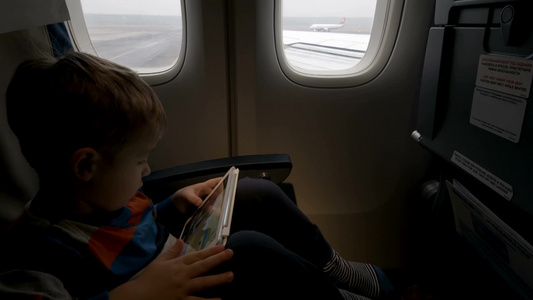 小男孩在飞机上玩平板视频