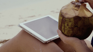 海滩上的女人喝椰子汁和使用平板电脑打字29秒视频