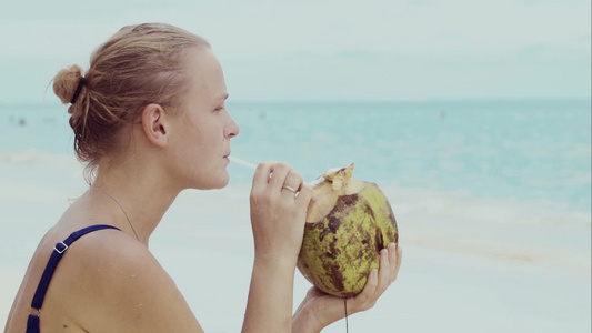 年轻的女人在海边喝椰子汁视频