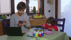 忙碌的母亲一边工作一边陪伴孩子画画26秒视频