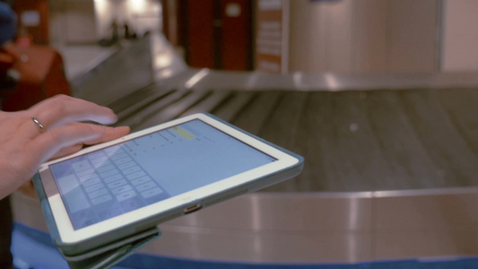 机场行李认领处附近的女性使用平板电脑打字信息视频