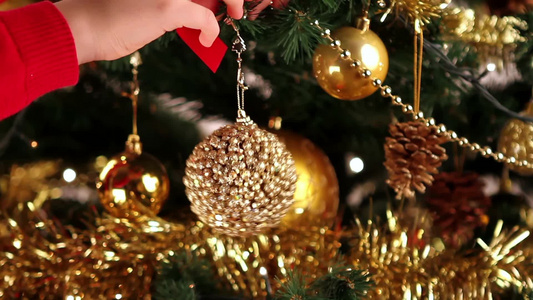 女孩在圣诞树树枝上挂装饰球。视频