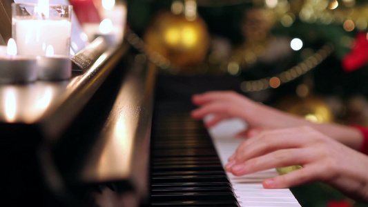 女孩在圣诞树附近弹钢琴视频