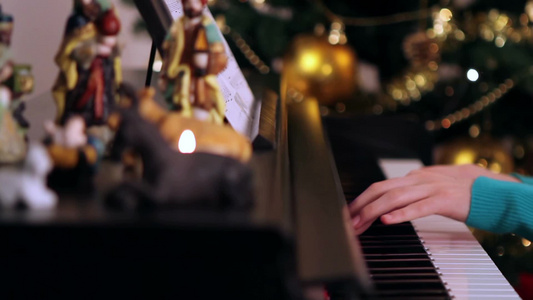 女孩在圣诞树附近弹钢琴视频