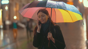 年轻的黑发女人撑着雨伞站在街上打电话17秒视频