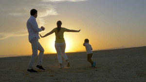 年轻快乐的父母和儿子在日落海滩12秒视频