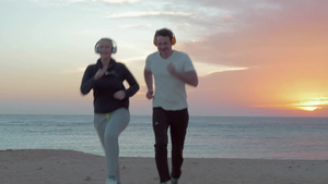 带着耳机年轻男女在海滩上慢跑12秒视频