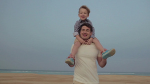 沙滩上一个孩子骑在父亲的肩膀上10秒视频