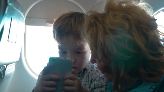 小男孩坐飞机玩手机视频