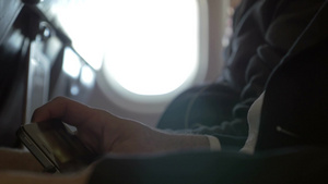 一名男性乘客在飞机上用智能手机看电影的特写镜头20秒视频