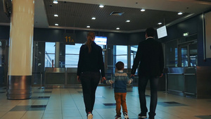 小男孩拉着爸爸妈妈的手他们一起走在空荡荡的机场航站楼29秒视频