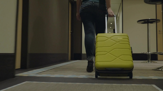 一个女旅行者带着手提箱在酒店走廊视频