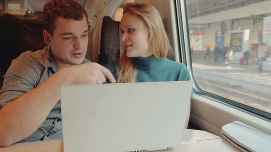 一对男女在火车中使用笔记本电脑交谈视频