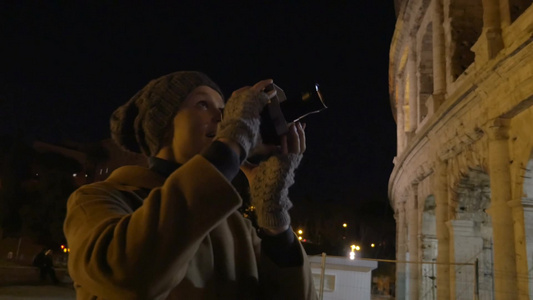 女性游客在夜间拍摄罗马斗兽场视频