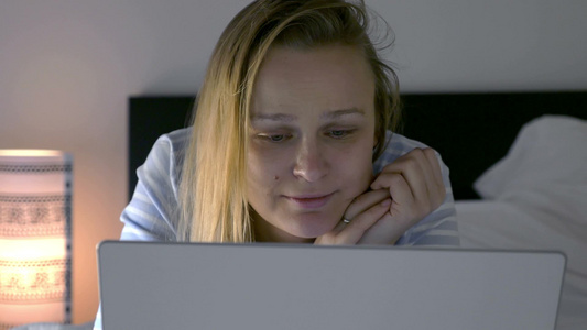 女人晚上躺在床上拿着笔记本电脑看剧视频