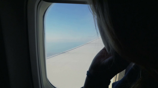 一个女人在飞机上看着窗外飞过云层视频
