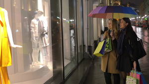 年轻女人拿着雨伞和购物袋一边看橱窗一边讨论衣服15秒视频