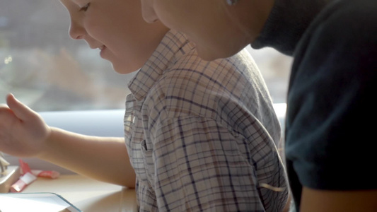 年轻女子陪男孩使用平板电脑视频