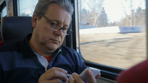 戴眼镜的老人乘火车旅行时用钢笔和智能手机浏览互联网31秒视频