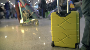 拥挤的机场地板上的男人拉着黄色行李箱离开15秒视频