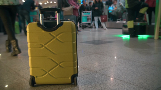 在车站里来来往往的人群中有一个黄色的行李箱视频