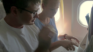 男职员和女职员在飞机上讨论着笔记本电脑里工作事务18秒视频
