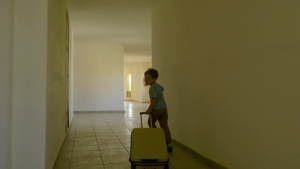 一个小男孩拉着他的行李箱沿着酒店走廊跑着18秒视频