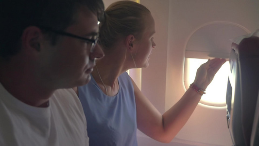 年轻男女乘飞机旅行打开窗户视频