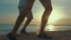 在太阳刚刚升起的海边父亲和成年儿子在跑步23秒视频