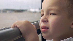 小男孩坐在公共汽车上看着窗外移动的风景露出微笑的表情10秒视频