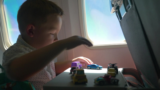 小男孩在乘坐飞机上玩小汽车玩具 视频