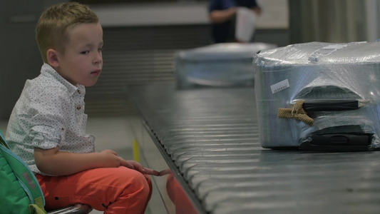 机场坐在传送带旁边的小男孩视频