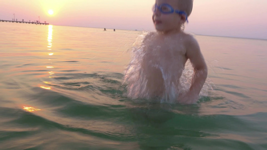 一个男孩在日落时戴着护目镜在海里洗澡视频