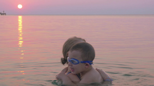 欢快的儿子和母亲日落时在水里交谈和拥抱16秒视频