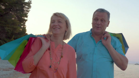 老年夫妇度假购物后在海岸上散步视频