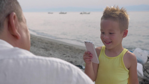 小男孩带着智能手机给海滩上的祖父母拍照片22秒视频