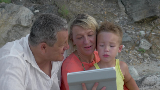 小男孩和他的祖父母用平板电脑上看东西视频