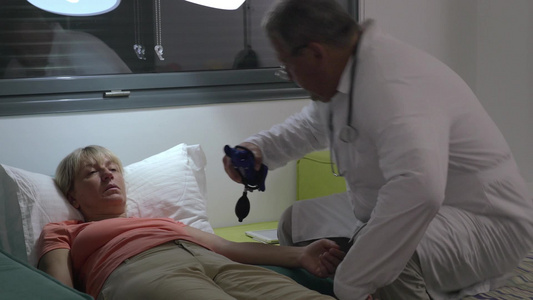 医生看一位老年妇女并检查血压视频