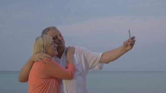 老年夫妇在海边用智能手机自拍视频