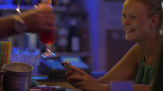 坐在酒吧柜台旁的微笑的年轻女人视频