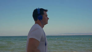 一个年轻人戴着耳机在海边跑步55秒视频