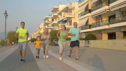 一家三口和祖父母晚上沿海滨度假的路上慢跑视频