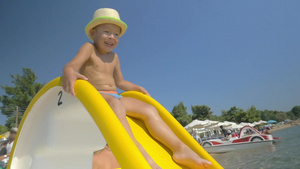 阳光下小男孩快乐在沙滩玩滑梯14秒视频