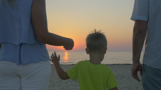 在海边母亲父亲和小儿子牵着手欣赏美丽的日落视频
