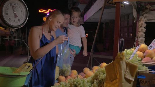一家三口晚上在市场上买水果视频
